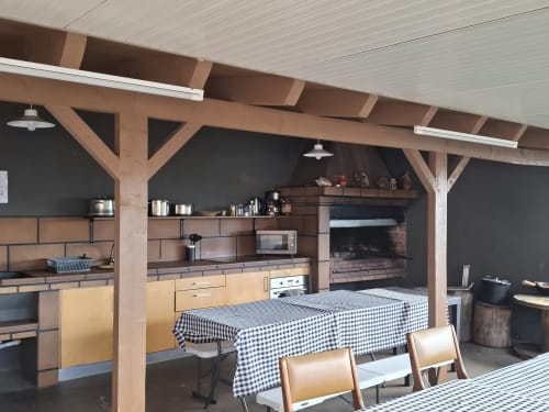 Spacious villa kitchen and dining area in Prazeres with wooden beams, fireplace, checkered tablecloth, and mountain views