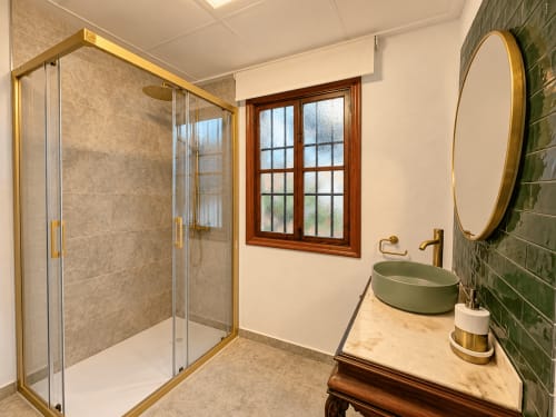Baño moderno en Casa Rural Garden Suites de Xàtiva con ducha tipo walk-in, lavabo de mármol y detalles en azulejos verdes