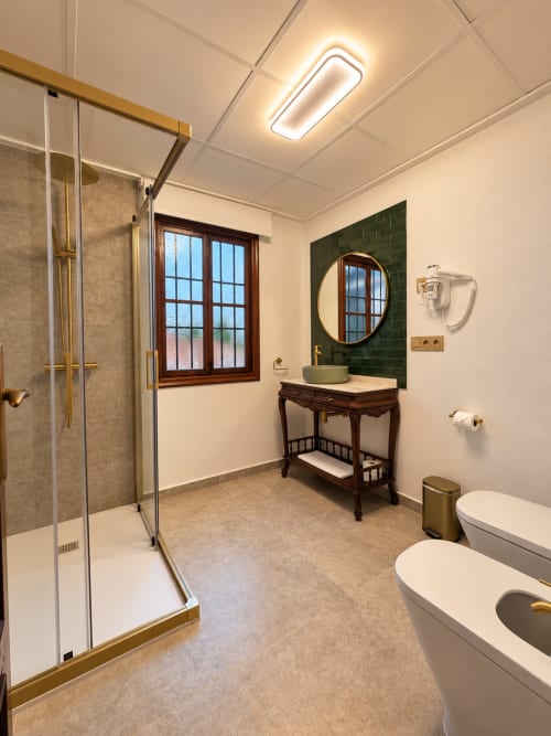 Baño moderno en Casa Rural Garden Suites de Xàtiva con ducha de paso, doble lavabo y pared de azulejos verdes