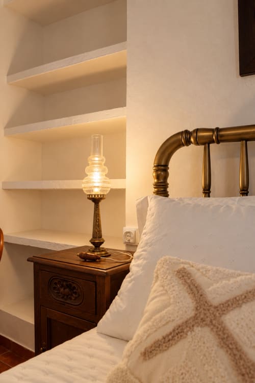 Dormitorio acogedor en Casa Rural Garden Suites en Xàtiva con cama de latón, mesita de madera, lámpara de aceite vintage y armario empotrado