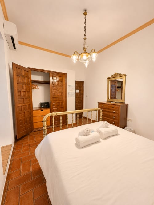 Elegante habitación doble en Casa Rural Garden Suites de Xàtiva con cama de latón, muebles de madera y lámpara de araña de latón