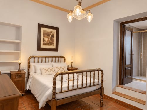 Elegante dormitorio doble con cama de latón y ropa de cama blanca en Casa Rural Garden Suites en Xàtiva, España