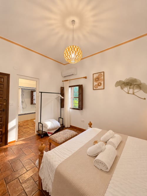 Amplio dormitorio doble en Casa Rural Garden Suites de Xàtiva con suelos de terracota, vigas de madera y vistas al jardín
