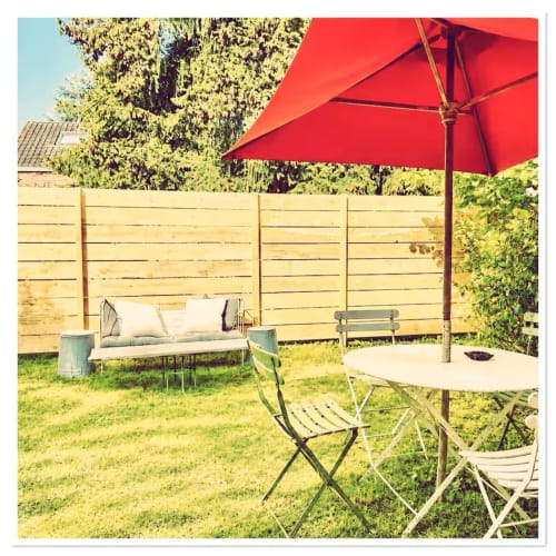 Charmant patio de jardin cottage aux Maraîchades en Sologne avec parasol rouge, coin détente et verdure luxuriante