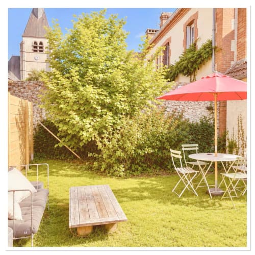 Charmant jardin du gîte Les Maraîchades avec salon de jardin, parasol rouge et verdure luxuriante en Sologne