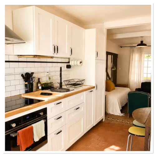 Cuisine cottage moderne aux placards blancs, comptoirs en bois et dosseret en carreaux blancs, chambre attenante aux Les