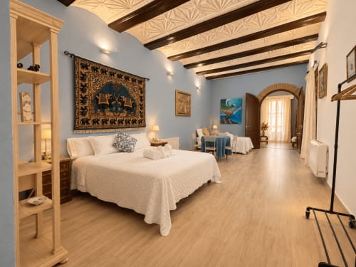 Amplio dormitorio en Casa Rural Garden Suites de Xàtiva con vigas de madera, cama blanca y vistas al jardín
