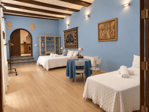 Espacioso dormitorio de apartamento en Casa Rural Garden Suites de Xàtiva con camas gemelas, paredes azules, vigas de madera y comedor privado