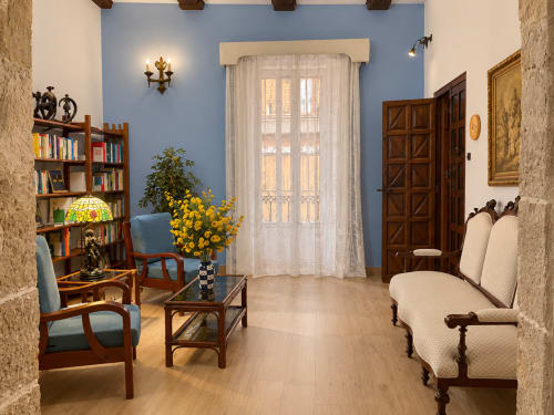 Elegante salón de Casa Rural Garden Suites, Xàtiva, con paredes azules, muebles de madera, estantería y vista al jardín