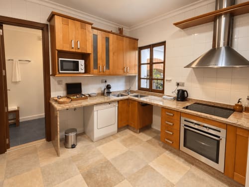 Cocina moderna con muebles de madera, encimeras de granito y electrodomésticos de acero inoxidable en Casa Rural Garden Suites