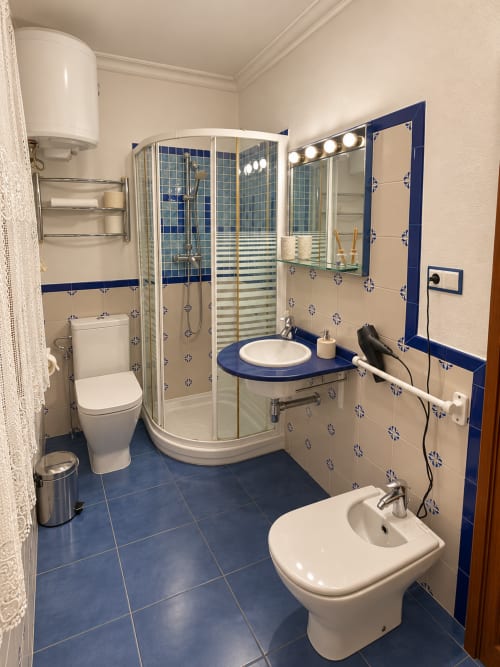 Baño moderno en Casa Rural Garden Suites de Xàtiva con ducha de azulejos azules, doble lavabo y bidé