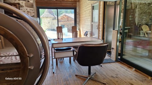Espace de travail du gîte Furanelle à Saint Etienne avec bureau en bois, chaise de bureau et vue sur la cour par de grandes fenêtres