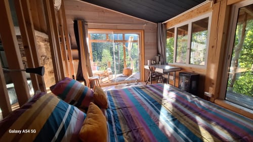 Chambre lumineuse de la Furanelle B&B à Saint Etienne avec literie rayée, poutres en bois, grandes fenêtres sur la forêt