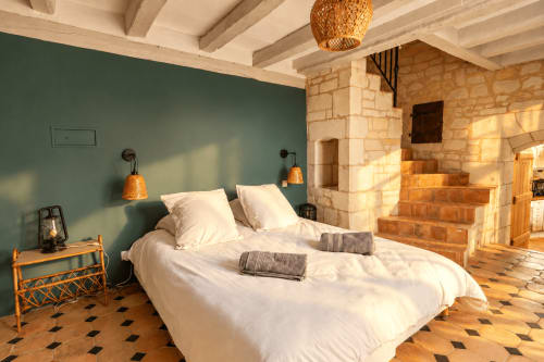 Chambre spacieuse du gîte Le Clos Divin à Doué-la-Fontaine avec poutres apparentes, murs turquoise et foyer en pierre
