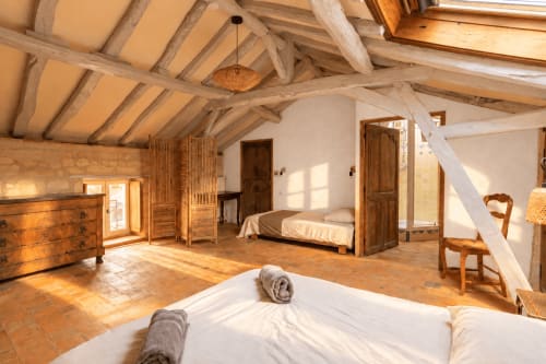 Spacieuse chambre loft à la maison d'hôtes Le Clos Divin à Doué-la-Fontaine avec poutres en bois apparent, deux lits et mobilier en bois