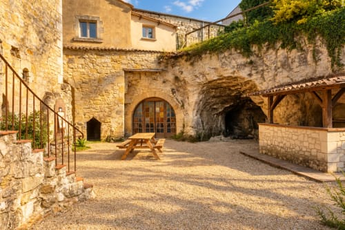 Cour médiévale en pierre du gîte Le Clos Divin à Doué-la-Fontaine avec portail en arche, table de pique-nique et lierre