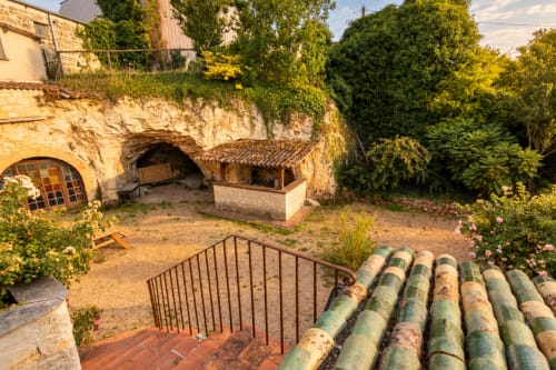 Cour en pierre du gîte Le Clos Divin à Doué-la-Fontaine avec entrée de cave voûtée historique et tuyaux verts