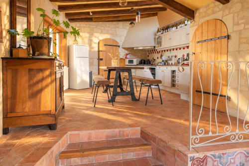 Cuisine rustique chaleureuse du gîte Maison Minérale au Clos Divin, avec poutres en bois, carrelage en terre cuite, coin repas