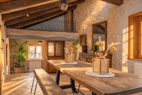 Salle à manger lumineuse du gîte Le Clos Divin avec poutres en bois, mobilier rustique, plantes et lumière naturelle