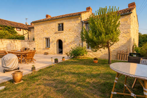 Cottage Maison Minérale au Clos Divin à Doué-la-Fontaine : façade en pierre, terrasse de jardin, mobilier bois et verdure