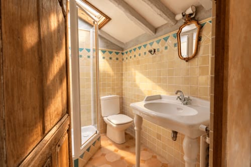 Salle de bain avec lavabo sur piédestal blanc, toilettes et cabine de douche au gîte Le Clos Divin à Doué-la-Fontaine