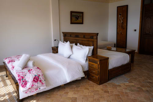 Spacious bedroom at Imsouane Surf Paradise with two wooden beds, white linens, pink floral bedding, and traditional Moroccan