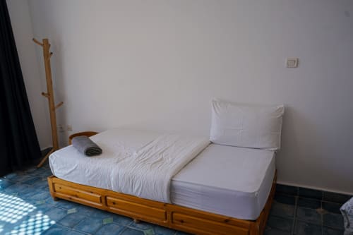 Minimalist bedroom at Imsouane Surf Paradise with wooden bed, white bedding, and ocean view in Agadir, Morocco