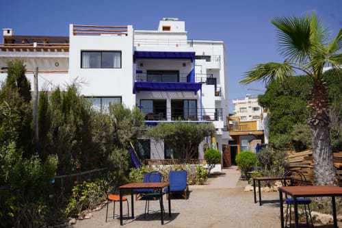 Imsouane Surf Paradise courtyard with white and blue buildings, palm trees, and outdoor seating in Agadir, Morocco