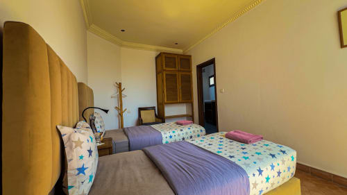 Twin bedroom at Imsouane Surf Paradise with star-patterned bedding, yellow accent wall, and ocean view balcony access