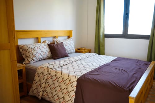 Cozy bedroom at Imsouane Surf Paradise with wooden bed, patterned bedding, and sea view windows in Agadir, Morocco