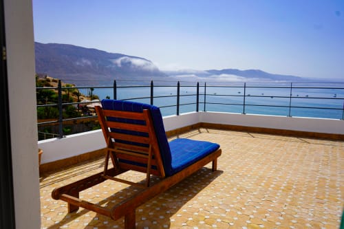Wooden chair with blue cushion on terrace overlooking Mediterranean Sea at Imsouane Surf Paradise hotel, Agadir