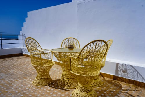 Yellow woven chairs and table on terrace at Imsouane Surf Paradise with white architecture and sea view, Agadir