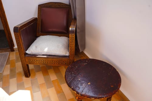 Tagante room at Imsouane Surf Paradise hotel featuring wooden armchair with burgundy cushions and round side table on