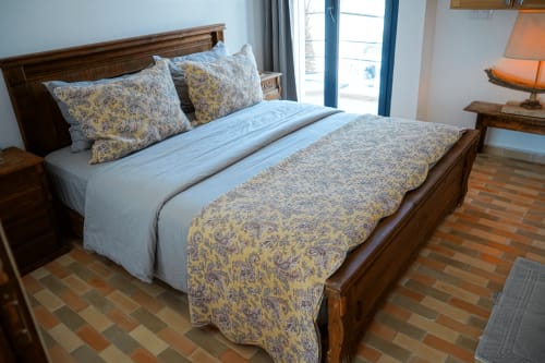 Wooden bed with yellow patterned bedding and pillows in Tiguemi apartment at Imsouane Surf Paradise, Agadir, with sea view