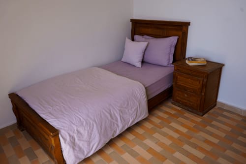 Cozy bedroom at Imsouane Surf Paradise with purple bedding, wooden furniture, and terracotta tiled floor in Agadir, Morocco