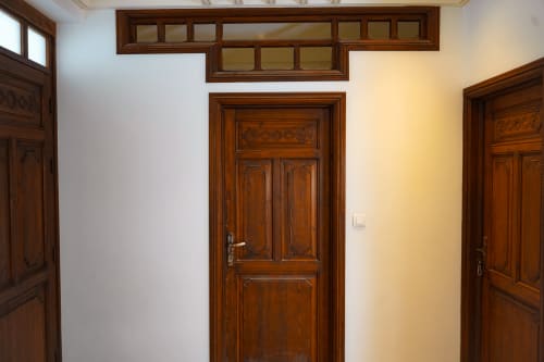Hallway with ornate wooden doors at Imsouane Surf Paradise hotel in Agadir, Morocco, showing traditional carved door frames