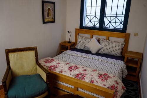 Mauringa 2 bedroom at Imsouane Surf Paradise with wooden bed, floral bedding, and windows overlooking the coast in Agadir,