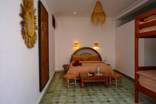 Loubana room at Imsouane Surf Paradise with ornate bed, terracotta furnishings, golden wall décor, and traditional Moroccan