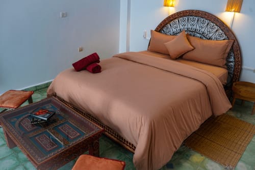 Loubana room at Imsouane Surf Paradise hotel featuring a queen bed with tan bedding, ornate headboard, and Moroccan decor