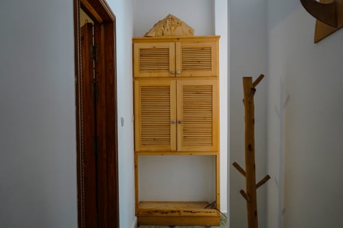 Wooden louvered cabinet and rustic branch coat rack in Loubana room at Imsouane Surf Paradise hotel, Morocco