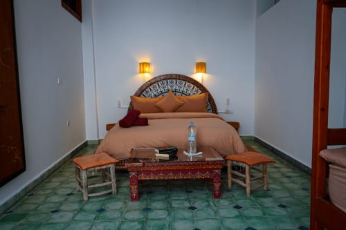 Loubana room at Imsouane Surf Paradise with ornate bed, decorative bench, and Moroccan tile flooring in Agadir