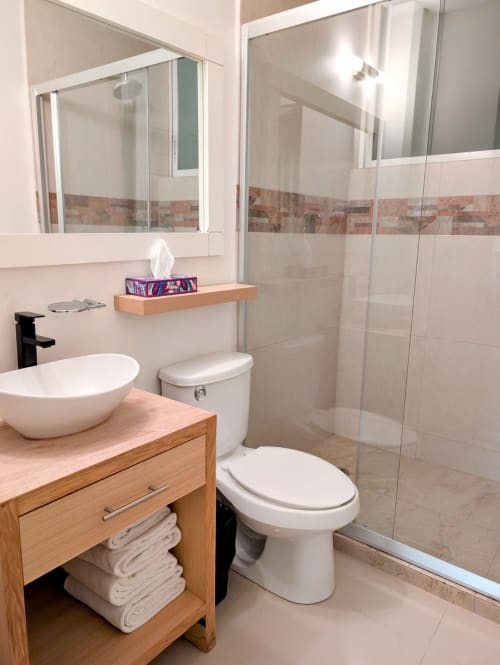 Baño moderno en Casa Donceles, Ciudad de México con lavamanos tipo vasija, ducha con mampara de vidrio, inodoro blanco y tocador de madera