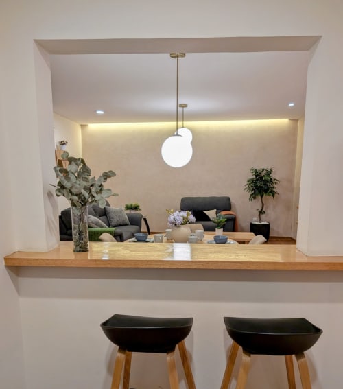 Cocina moderna con encimera de madera, taburetes negros y vista al salón del departamento Casa Donceles en Ciudad de México