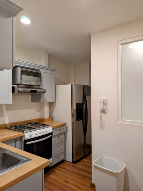 Cocina moderna del apartamento Casa Donceles en Ciudad de México con electrodomésticos de acero inoxidable, encimeras de madera y blanco