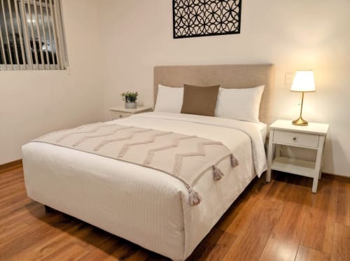 Dormitorio del apartamento Casa Donceles en Ciudad de México, cama queen, cabecero beige, mesilla blanca y piso de madera