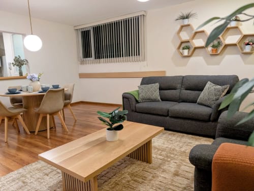 Sala moderna de Casa Donceles en Ciudad de México, sofá gris, mesa de madera, comedor y plantas en macetas
