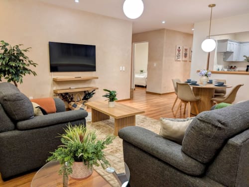 Sala de estar moderna del departamento Casa Donceles en Ciudad de México con sofás grises, muebles de madera, TV y cocina abierta