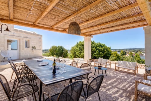 Terrazza esterna della villa Casolare Treggi a Ostuni con tavolo da pranzo, pergolato in legno e vista sulla campagna