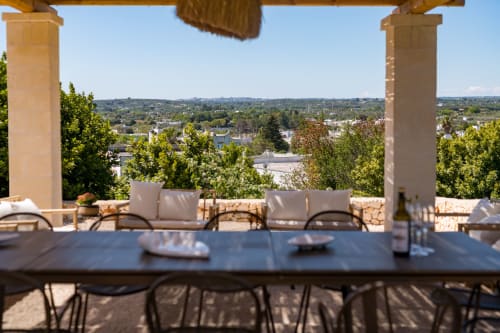 Terrazza di lusso a Ostuni con tavolo da pranzo, lounge e vista panoramica sulla campagna