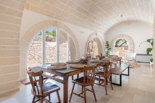 Elegante zona dining nella villa Casolare Treggì, Ostuni, con volta in mattoni, tavoli in legno e vista sul giardino